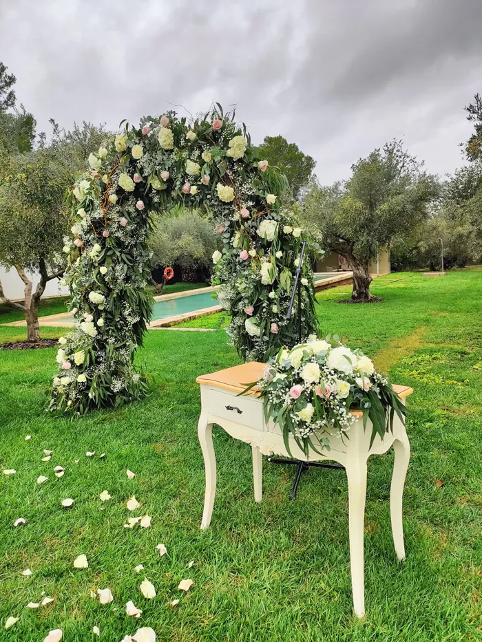 Arco floral de boda con flores blancas y mesa de ceremonia en el jardín